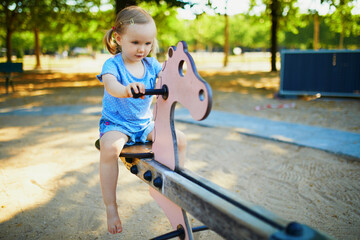 Adorable little girl having fun on seesaw