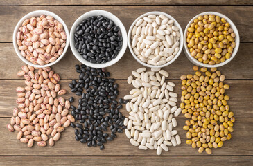 Naklejka premium Closeup of assorted beans on white bowls over wooden table
