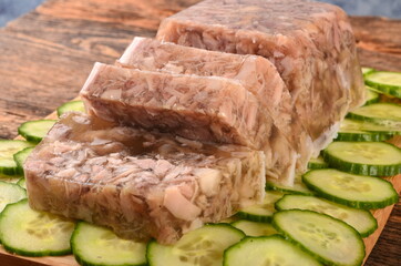 Meat jelly or brawn on a plate. Homemade head cheese on cucumber slices