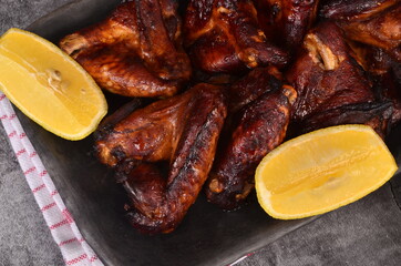 Grilled chicken wings on a plate with lemon and sauce. Roasted in oven crispy sticky honey chicken wings