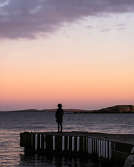 Fototapeta premium silhouette of a person standing on the pier at sunset in Norway