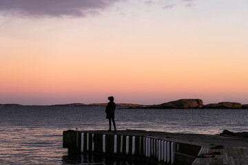 silhouette of a person standing on the pier at sunset in Norway