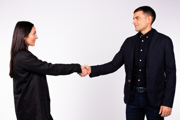 Young business partners in office clothes shake hands on a white background.