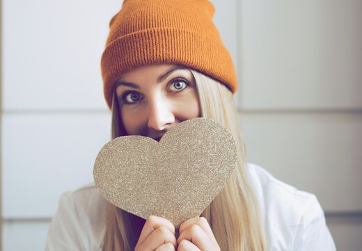 Pretty hipster girl with a big paper heart on the hands. Portrait of smailing girl ready for Snt. Valentines day. Cupid day. Love