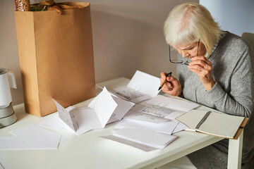 Serious pensioner leaning over an electricity bill