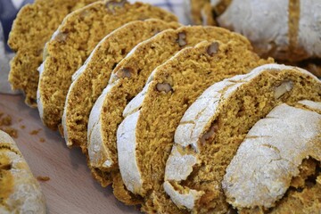 Round loaves of rustic bread on a blue and white square patterned dishcloth with two of the loaves cut into slices