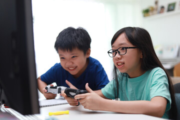 Boy and girl sitting in the living room playing a video game in front of monitor screen together. Soft focus image.