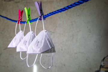 Sammlung von FFP2 Viren-Schutzmasken, aufgehängt mit Wäscheklammern auf einem blauen Seil vor...
