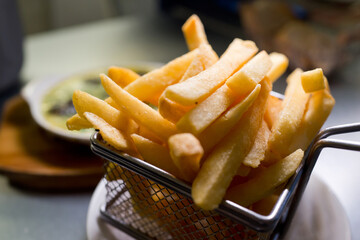 Close up French fries in a metal basket. Soft focus image.