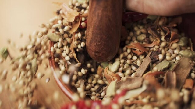 Close up of Hands hitting or smashing Indian mixed Masala spices in the wooden bowl or Spice Grinder - Concept of Preparation of Indian masala spices