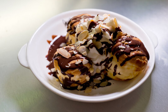 Profiteroles with ice cream, almond and chocolate on a plate. Soft focus image