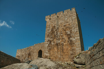 Stone wall with gateway and tower over rocky hill at the Linhares da Beira Castle. A medieval hamlet with unique architecture in Portugal.