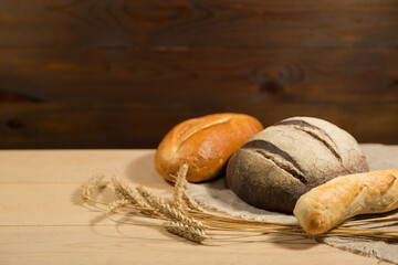 homemade baked goods and ears of wheat on a wooden background. different breads are on wood table