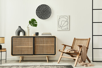 Stylish scandinavian living room interior of modern apartment with wooden commode, design armchair, carpet, leaf in vase, table lamp and personal accessories in unique home decor. Template.