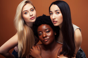 Obraz premium young pretty asian, caucasian, afro woman posing cheerful together on brown background, lifestyle diverse nationality people concept