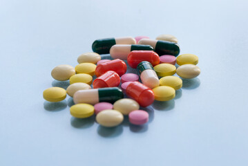 Colorful pills and capsules isolated on a blue background. Medical health or drugs addiction concept.