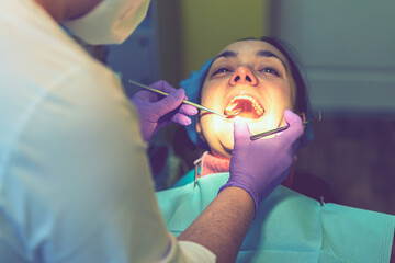 Male dentists examining and working on young female patient.Dentist's office. Real woman in a chair at the dentist. toned