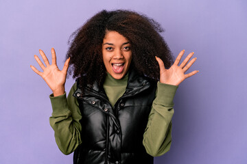 Young african american curly woman isolated on purple background receiving a pleasant surprise,...