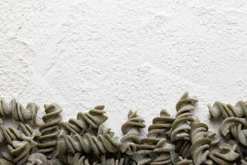 Spinach Fusilli dry pasta on concrete table with space for your text. Gluten free pasta. 