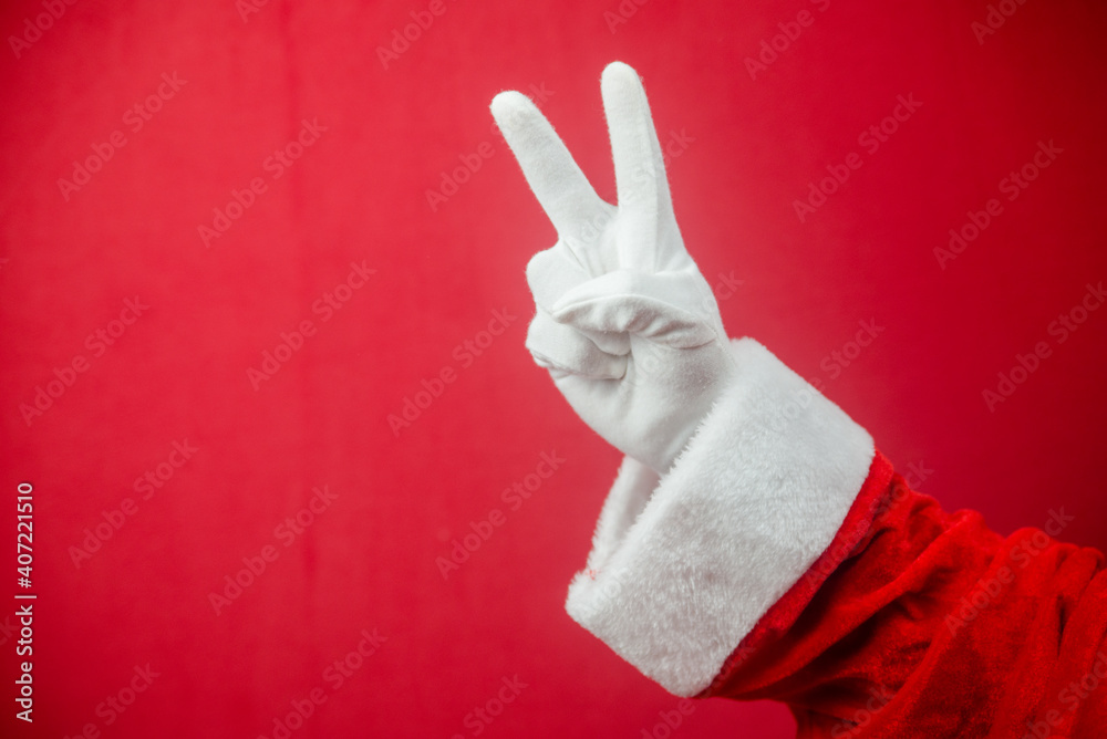 Wall mural santa claus showing v victory sign. closeup photo of gloved hand. merry xmas and happy new year time