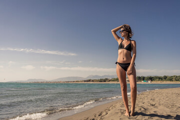 Beautiful young female in bikini on gorgeous sandy beach enjoying summertime vacation