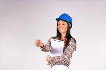 Smiling woman in a blue hard hat. Engineer with documents on a white background stretching out his...