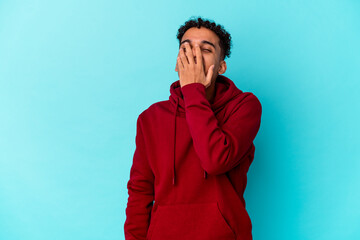 Young african american curly man isolated on blue laughing happy, carefree, natural emotion.