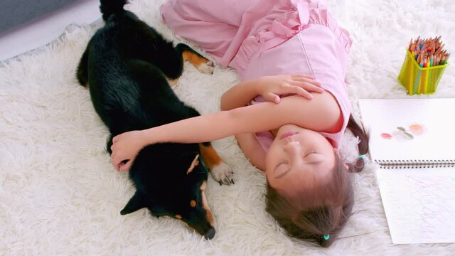 Asian little girl sleeping with her dog on the floor at home.