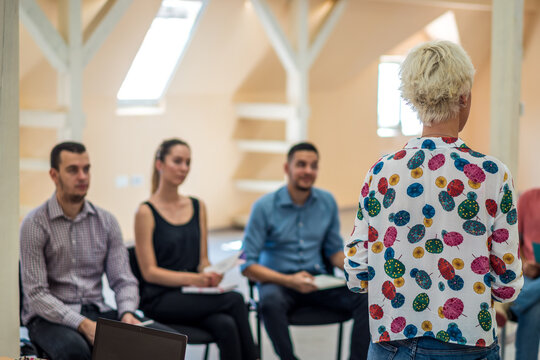 Group of people listening to a presentation. Woman handling the workshop like a pro while speaking on seminar for professional development and team building
