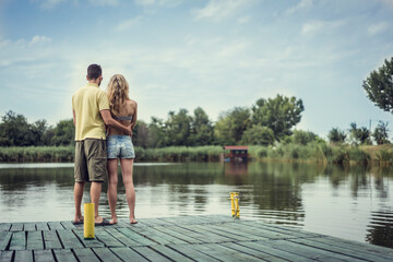 Beautiful young and handsome couple outdoors enjoying summertime in nature next to river lake. Man hugging woman. Love is forever