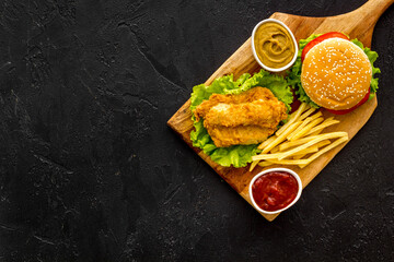 Top view of delicious burgers on on wooden board. Fried potatoes and chicken