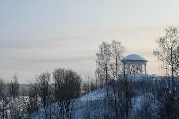Scenic winter landscape of sloping shore of Vyatka river. Naked trees. White Rotunda in the...
