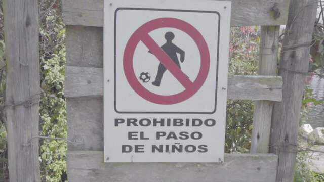 White sign with a red crossed circle forbids the passing of children through a door. The sign translates to "Children passing forbidden".