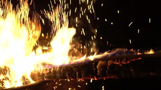 Burning container beat by wood stick, making sparkles in slow motion
