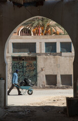 An archway looking out over a street  with a man pushing a wheel barrow scene in Ghadema, the medina or old city of Tripoli, Libya.