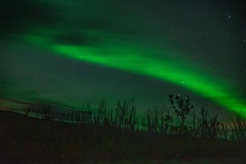 Strip of a northern light with clouds on the sky