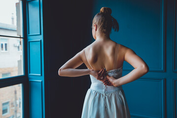 ballerina dancing against the blue wall. View from the back to the camera