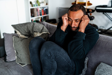 Fototapeta premium Sad 40 years old man sitting on the sofa at home