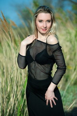 Beautiful sexy blonde girl in black blouse posing in reeds