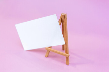 Wooden easel with white sheet. Vector illustration. Pink background.