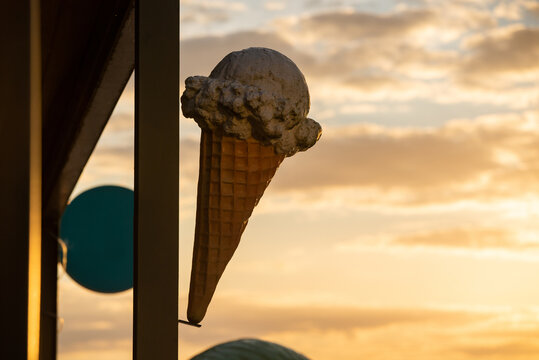 A huge waffle with a scoop of ice cream stuck to the dasada of the pudding against the sky