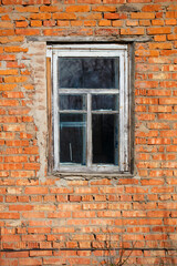 Vertically brick wall with a window in an old rustic frame.