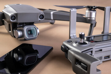 a drone, its controller and a smartphone on brown background