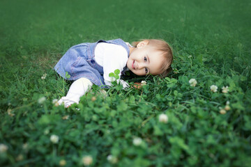 A child lies smiling in a clover field. Lovely little girl.