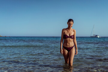 Fototapeta na wymiar Beautiful young woman in bikini on vacation swimming in sea and enjoying in sand beach. Happy female enjoying summer time holiday on beach.