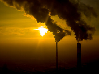 Power Plant emissions seen above the city  during sunrise. Environmental pollution. Factory pipe polluting air. Smoking pipes Aerial view
