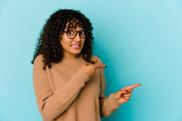 Young african american afro woman isolated shocked pointing with index fingers to a copy space.