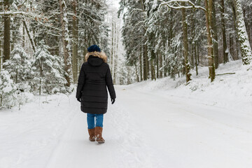 Woman walking on a winter forest park,back view. outdoors shot.