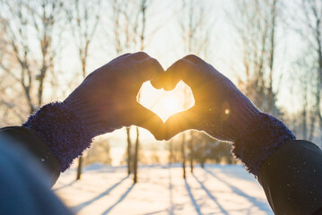 Woman making heart symbol with hands.sunny winter evening, sunrays, Valentines day, Love concept.
