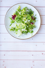 White ceramic plate with fresh salad on wooden background